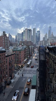 a city street filled with lots of traffic under a cloudy blue sky and tall buildings