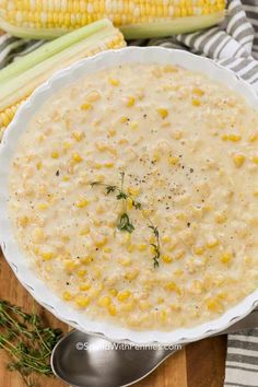 a white bowl filled with corn on the cob and garnished with herbs