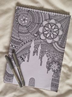 a coloring book with a pen sitting on top of it next to an ink drawing