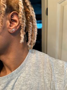 a man with dreadlocks wearing a grey shirt and ear piercings in his ears