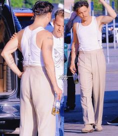 two men standing next to each other in front of a car and one man with his hand on his head