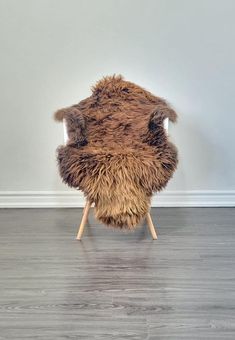 a chair made out of fur with wooden legs on a hard wood floor in front of a white wall