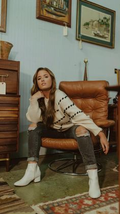 a woman is sitting in a chair with her legs crossed and looking at the camera