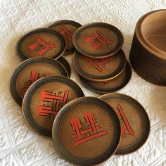 six brown plates with red designs on them next to a cup and saucer sitting on a white tablecloth