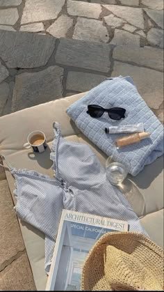 a hat, sunglasses and other items are laid out on a blanket next to a cup of coffee