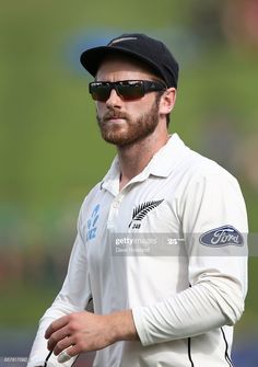 a man in white shirt and black hat with sunglasses on his head looking off to the side