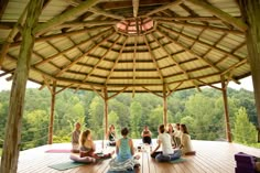 a group of people sitting on top of a wooden floor in front of a gazebo