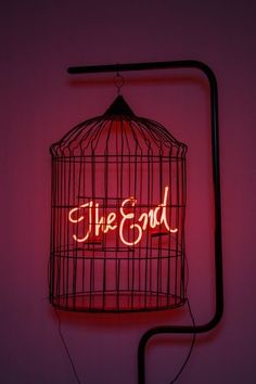 a neon sign that says the good in a birdcage hanging on a wall