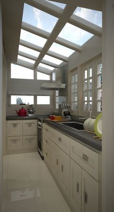 a kitchen with white cabinets and counter tops under a skylight that is shining through the windows