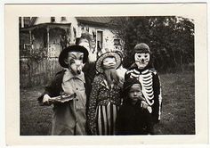 an old black and white photo shows three children dressed up in skeleton costumes, one holding a doll