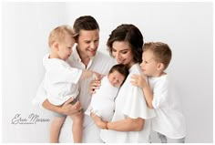 a man and woman holding two small children in their arms while posing for a family photo