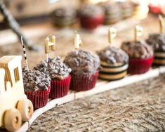 cupcakes with chocolate frosting on them are lined up in a row, along with a toy train