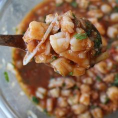 a spoon full of food that is on top of a glass bowl with some sort of sauce