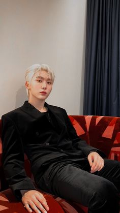 a young man sitting on top of a red couch