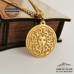 a gold necklace with an image of a woman's face in the center on top of a book