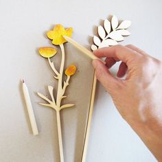 a person holding a pencil near some cut out flowers