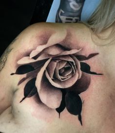 a black and white rose tattoo on the back of a woman's shoulder