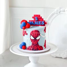 a spiderman themed birthday cake on a white pedestal