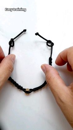 two hands are holding black string bracelets