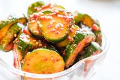 a glass bowl filled with sliced cucumbers covered in sauce and sprinkles