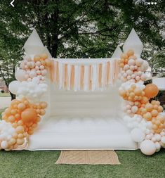 an inflatable arch with balloons and streamers on the grass at a wedding