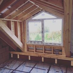 an attic with wooden framing and windows on the wall, in progress to be installed