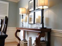 a dining room table with candles and pictures on the wall above it, along with other decor items