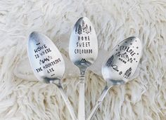 three spoons with the words home is sweet colorado on them sitting on a furry surface