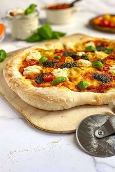 a pizza sitting on top of a wooden cutting board next to other food and utensils