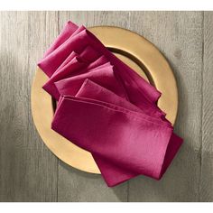 the napkins are folded on top of each other in front of a gold plate