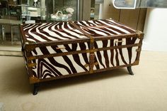 a zebra print trunk sitting on top of a floor next to a glass display case