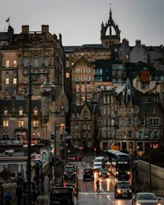 cars are driving down the street in front of buildings at night with traffic lights on