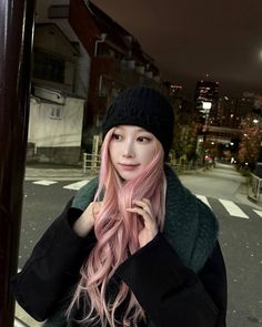 a woman with long pink hair standing on the street