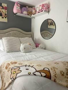 a bedroom with a bed, mirror and stuffed animals on the shelves above it's headboard