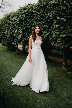 a woman in a white dress standing on grass