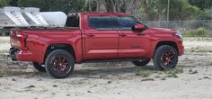 a red truck parked on top of a dirt field