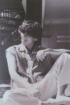 black and white photograph of a young man sitting on the floor with his legs crossed