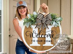 a woman holding a welcome to our home sign