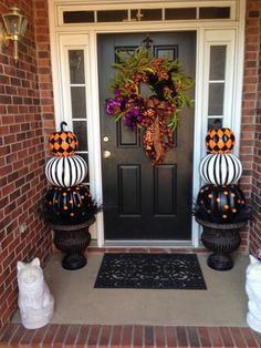 two pumpkins sitting on top of black and white decorations in front of a door