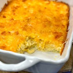 a casserole dish with cheese and meat in it sitting on a table next to utensils