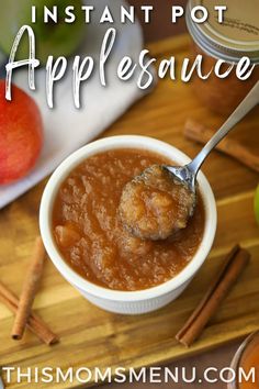 applesauce in a white bowl with spoon on wooden cutting board next to apples and cinnamon sticks