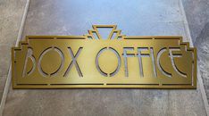 a metal sign that says box office on the side of a building with gold lettering