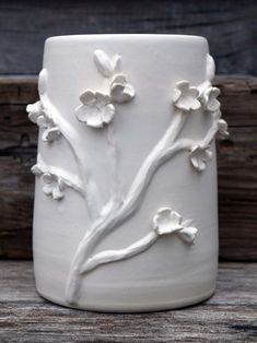 a white vase sitting on top of a wooden table