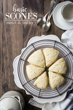 some biscuits are sitting on a plate with tea cups and spoons next to it