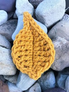 a yellow knitted object sitting on some rocks