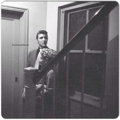 a man in a suit and tie is sitting on the stairs looking at his reflection