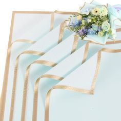 a bouquet of flowers sitting on top of a white table cloth with gold ribbon around it