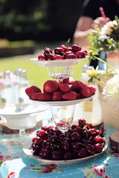 three tiered plates filled with cherries on a table