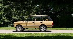 an old car is parked on the side of the road in front of some trees