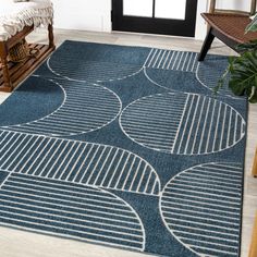 a blue rug with white circles on it in front of a black door and chair